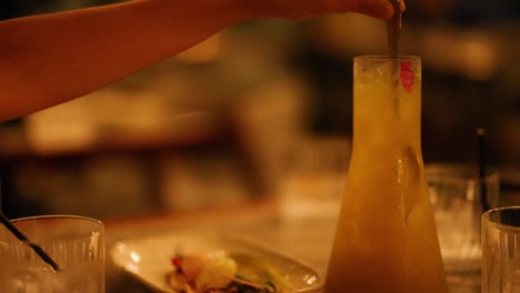 a hand stirs a cocktail in a dimly lit setting, creating a warm, inviting atmosphere. captured on the gold coast, australia