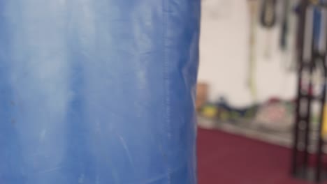 young muscular athlete works out on a punchbag indoors