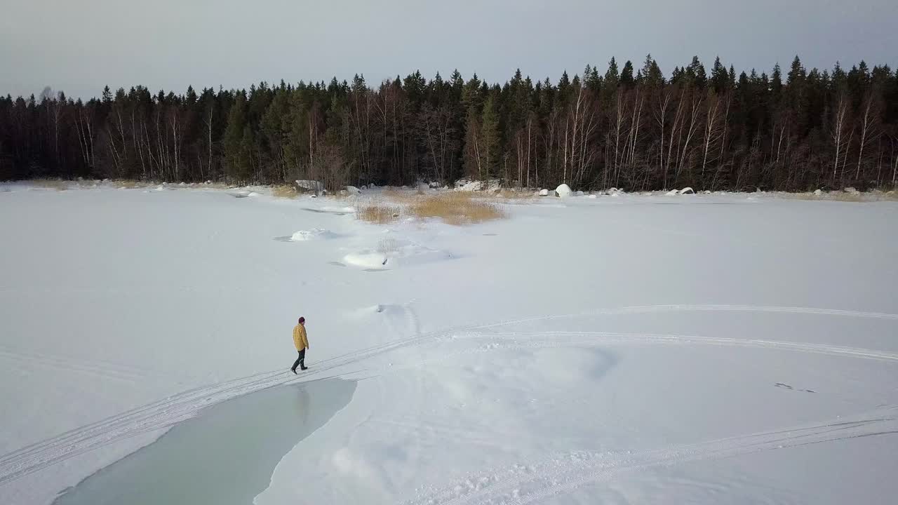 disparo de drones, siguiendo a un anciano caminando en un lago invernal congelado en el norte de finlandia, lejos de la civilización