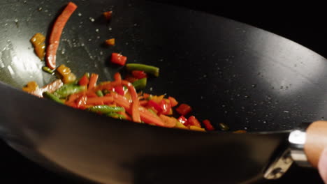 stir-frying peppers in a wok