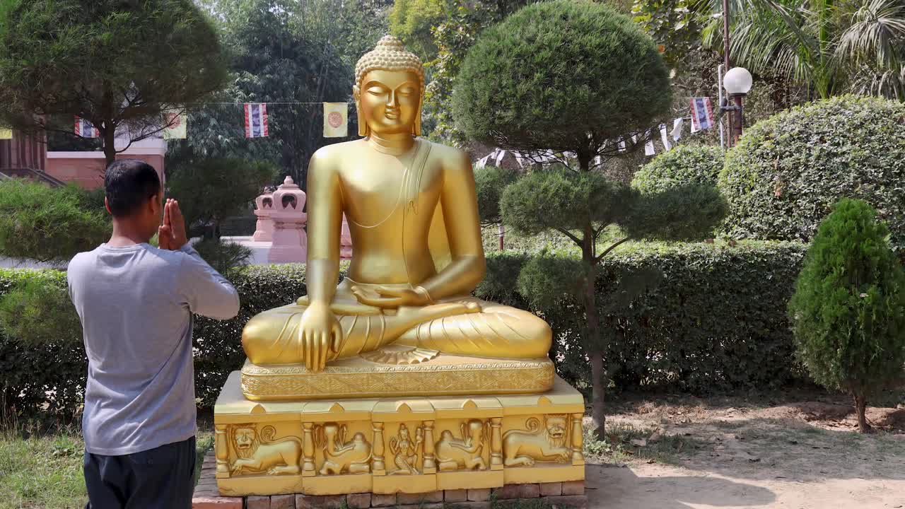 man offering salutation worships to holy golden buddha statue at outdoor
