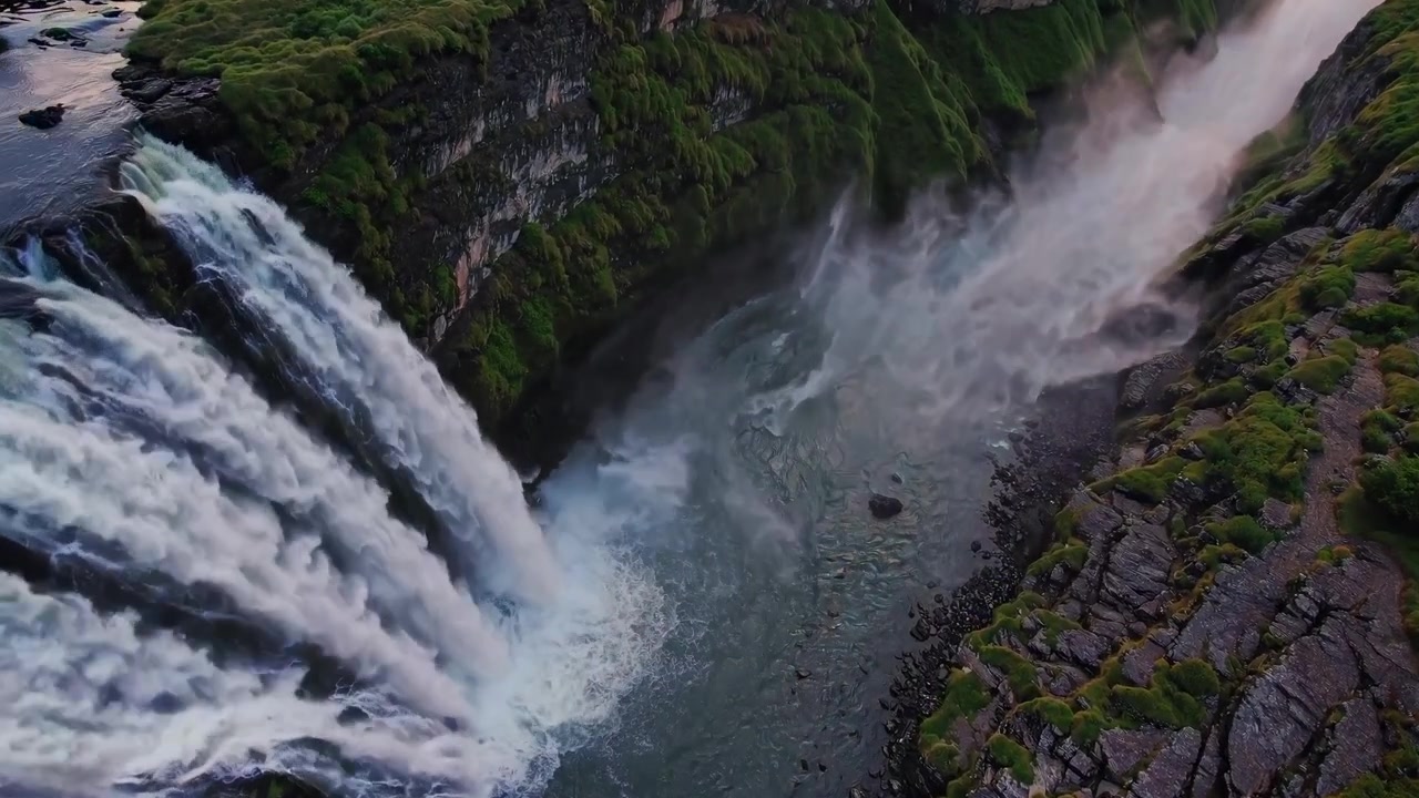 Vista Aérea de uma Majestosa Cachoeira Caindo por Penhascos Verdes ao Pôr do Sol