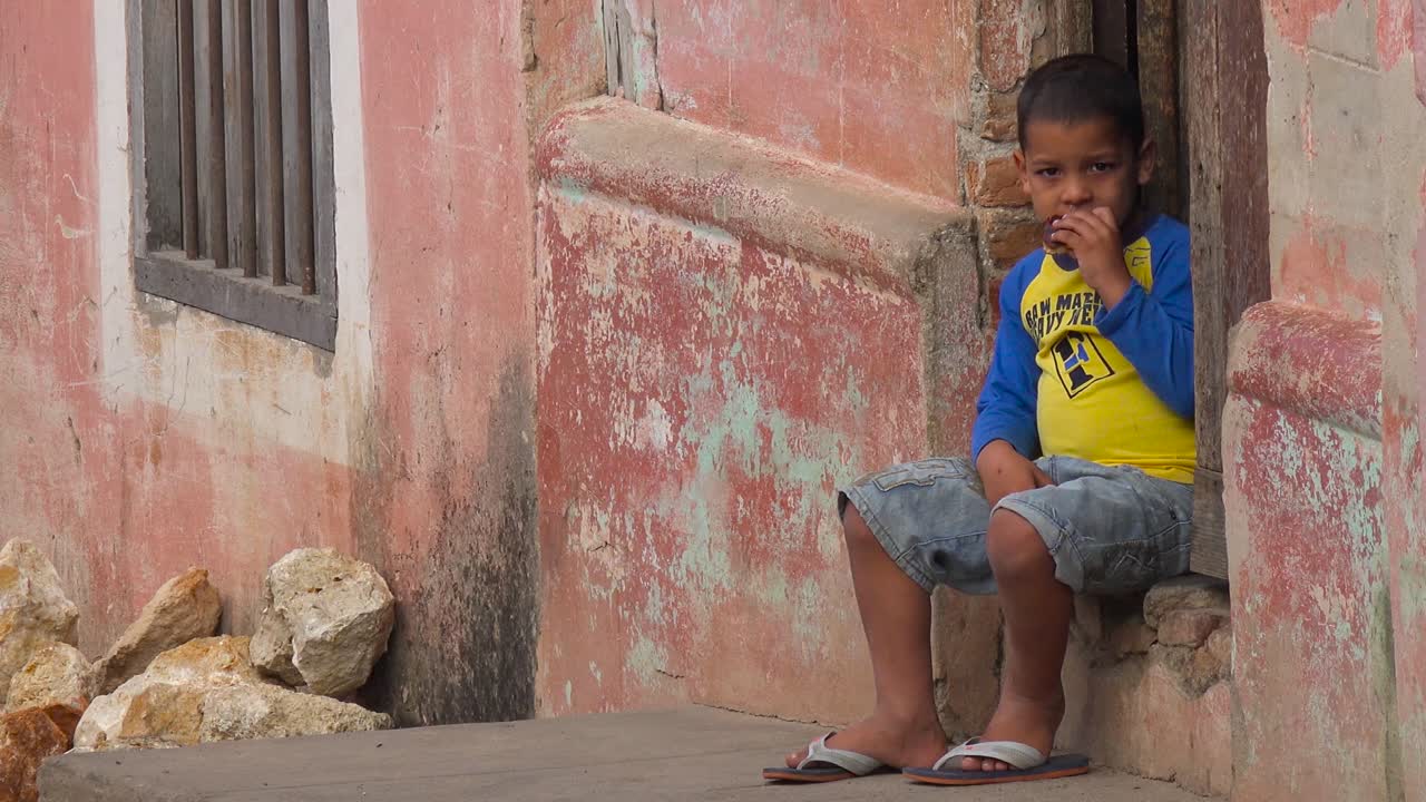 un niño pequeño se sienta en la calle mirando a los transeúntes en trinidad cuba