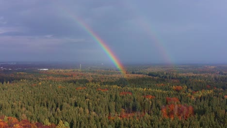 aerial of a colorful double rainbow over an autumn forest