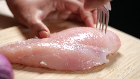 cerrado de pecho de pollo crudo siendo pinchado con un tenedor