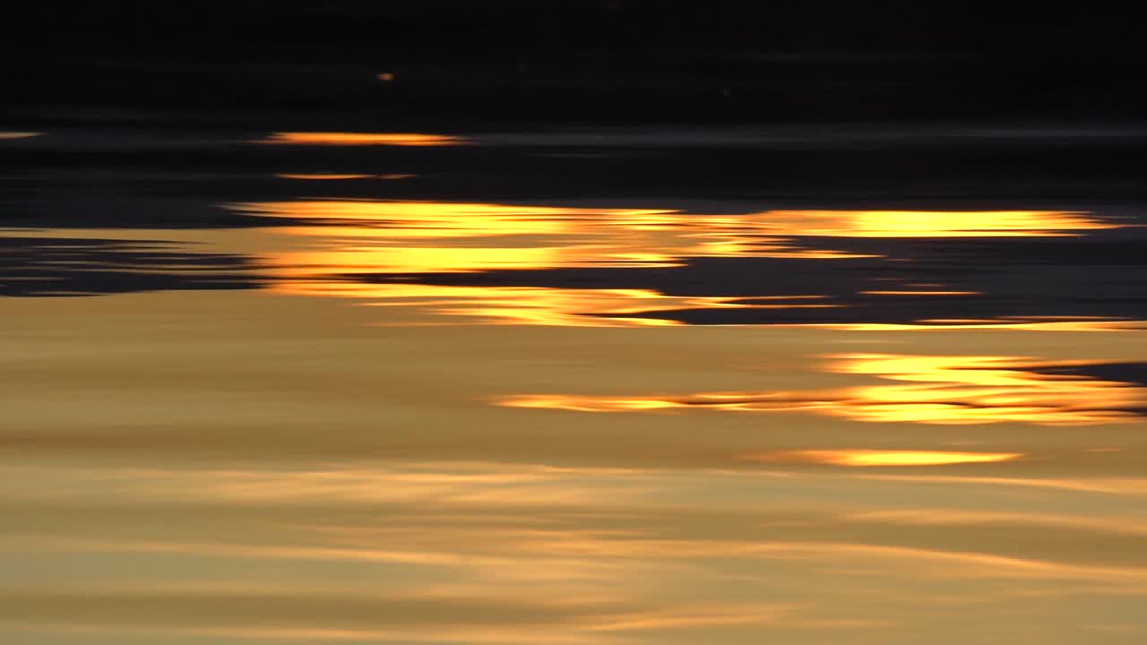 Reflection of sunset on lake surface in slow motion