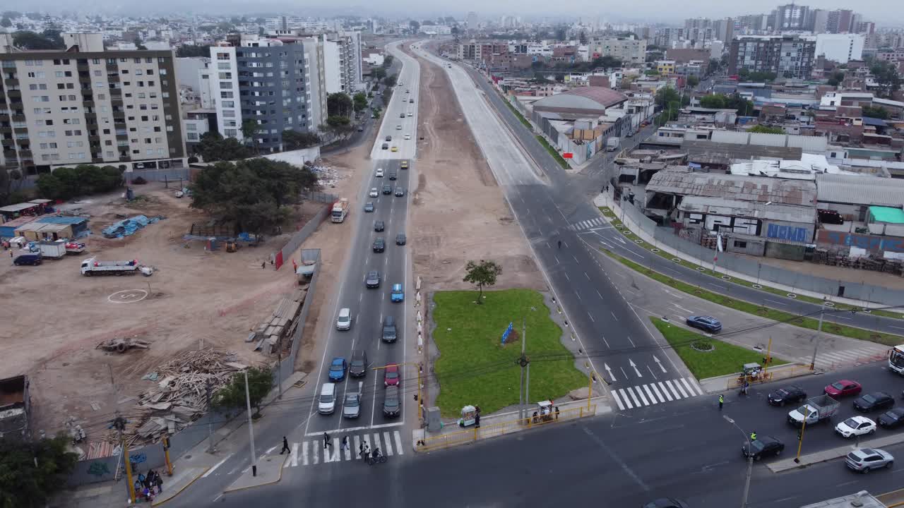 A newly built express way, named "Via Expresa Sur". Drone flies forward while slowly tilting the camera up showing the many buildings in the horizon. Located in Lima, Peru