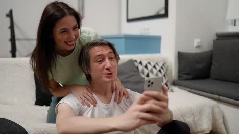 Happy-couple,-video-call-and-phone-with-smile-on-bed-in-the-bedroom-relax-at-home-in-happiness