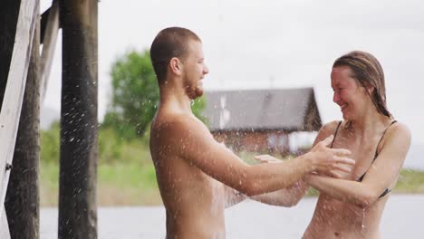 caucasian couple having a good time on a trip to the mountains, standing by a lake, taking a shower