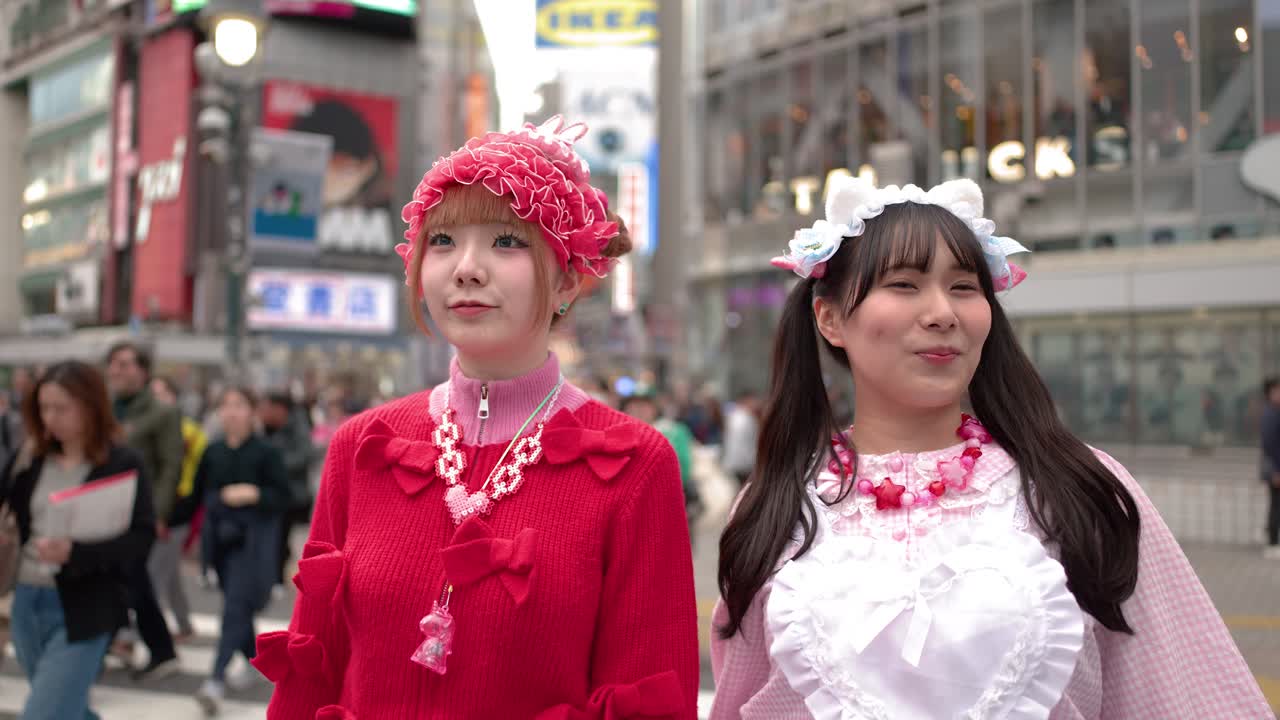 Due donne con colorati abiti in stile decora giapponese stanno insieme all'affollato incrocio di Shibuya Crossing.