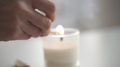 slow motion of hand lighting up white candle with matchstick inside home for dinner,close up