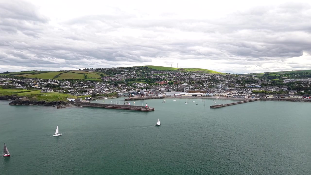 Smuk droneoptagelse af en lille yacht, der nærmer sig Wicklow Harbour, Irlands kystlinje