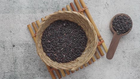 close up of black rice in a bowl and wooden spoon