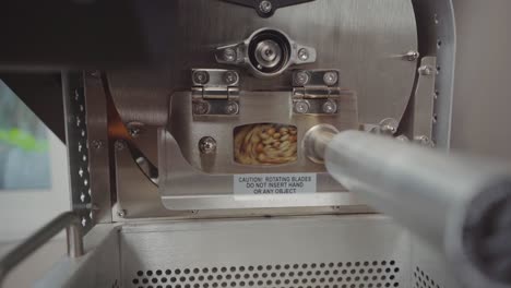 Processing-coffee-beans-into-coffee-roaster-machine-with-small-window,-static-timelapse