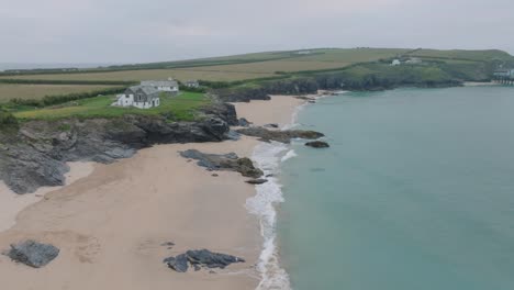 houses on low sea cliffs next to clean sandy beach with blue water. mother ivey's bay, cornwall, uk.