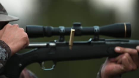 a man in camouflage fires a rifle and a bullet casing flies through the air