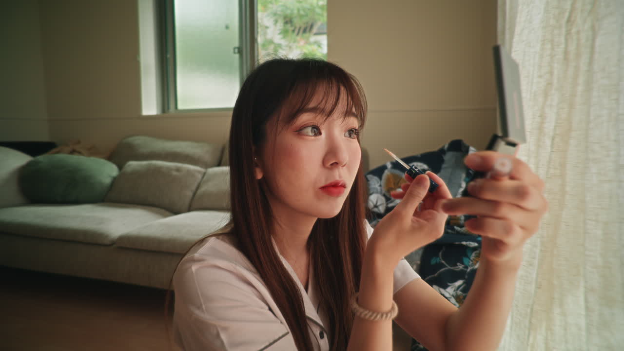 Woman applying makeup indoors