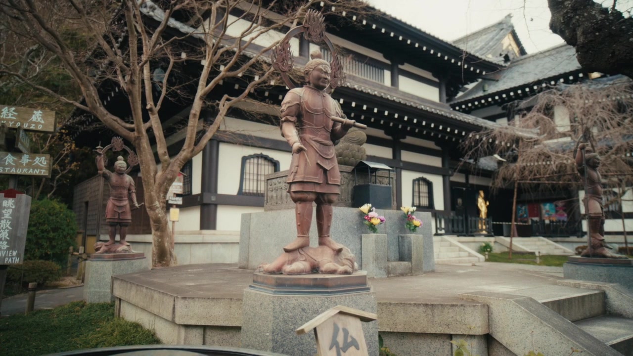 Vista frontale di statue ornate in bronzo di divinità guardiane posizionate su piedistalli di pietra davanti alla sala principale del tempio Hase-dera a Kamakura