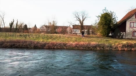 sideways drone dolly shot flying over river and following three men walking along the river