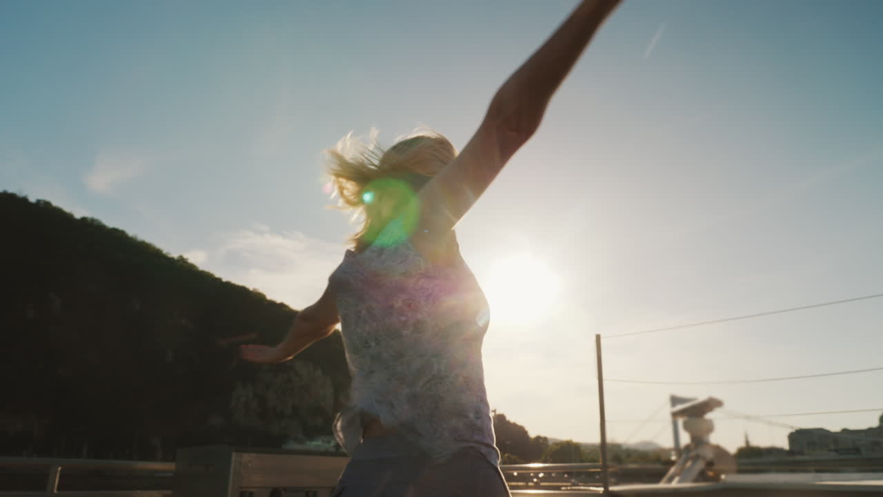 una mujer baila en un yate contra el telón de fondo del sol poniente 1