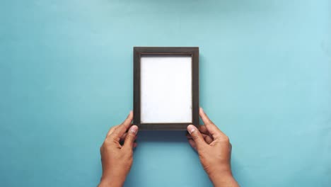 hands holding an empty wooden picture frame