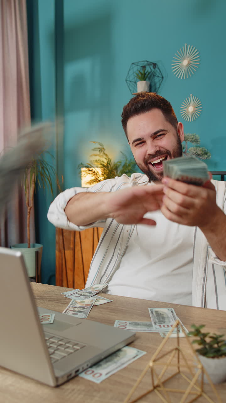Hombre de negocios rico y feliz en la oficina trabajando en su portátil, con dinero en efectivo