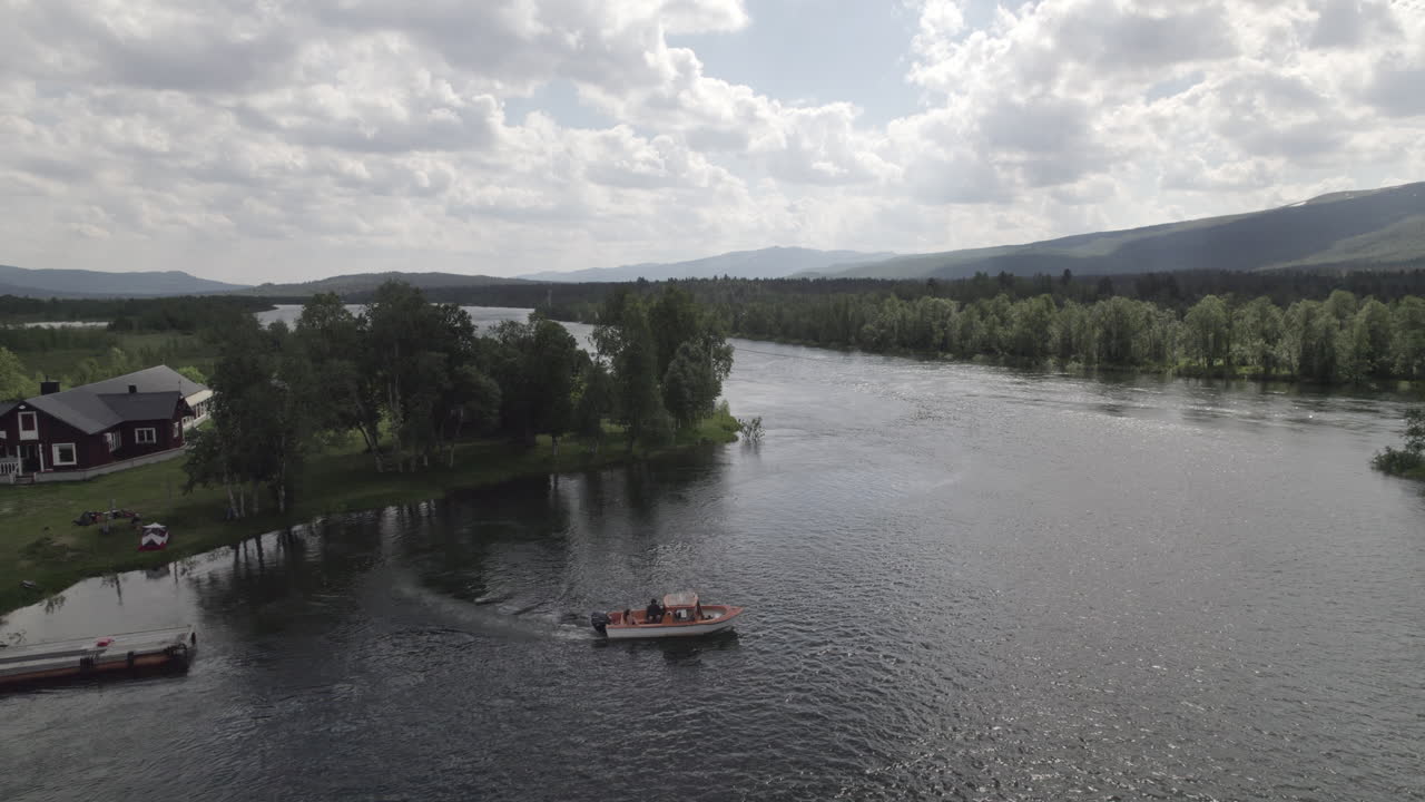 Veduta aerea di un motoscafo in partenza da un molo su un fiume in un paesaggio forestale svedese nella Svezia settentrionale, Lapponia, giorno nuvoloso, Adolfström.