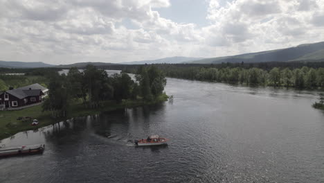 Aerial-View-of-a-Motorboat-departing-from-a-Dock-on-a-River-in-a-Swedish-Forest-Landscape-in-Northern-Sweden,-Lapland,-Cloudy-Day,-Adolfström