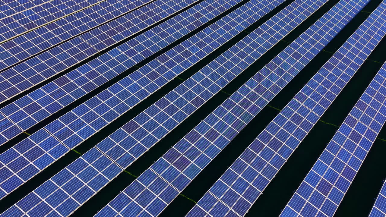 Pannelli solari disposti in file catturano la luce solare in un progetto di energia rinnovabile situato in una zona rurale durante una giornata serena.
