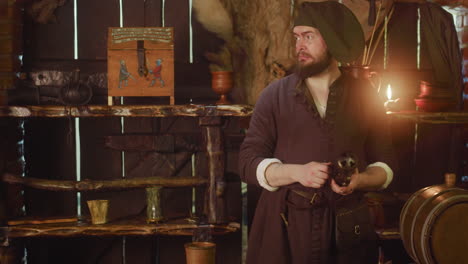 el portero se sacude las manos y revisa la linterna en la tienda. el barman malhumorado se prepara para vender bebidas y mercancías en una taberna medieval. escena de cuento de fantasía