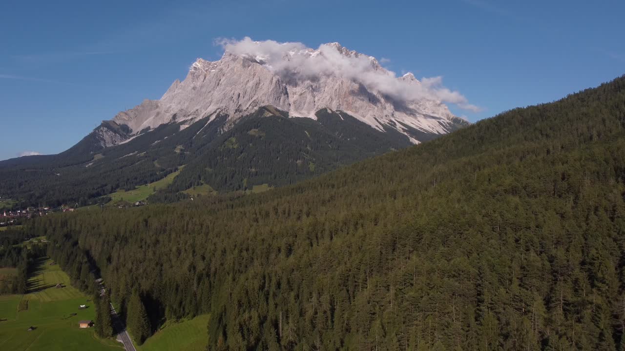 산이 전경의 나무로 뒤덮일 때까지 화창한 날 드론으로 촬영된 화려한 마테호른의 하강 드론 샷