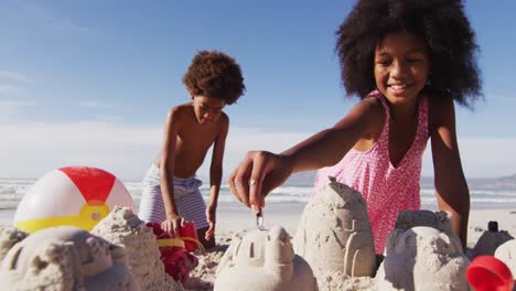 hermano y hermana afroamericanos jugando con arena en la playa