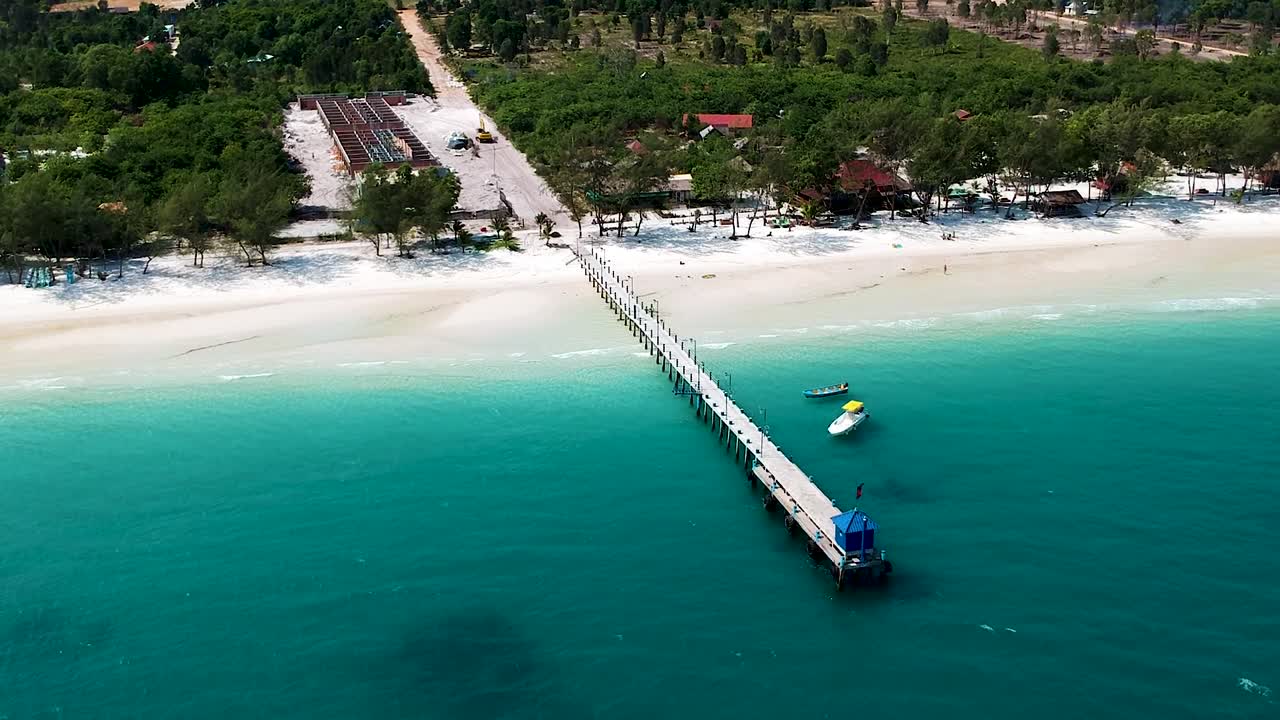 aerial de una hermosa playa de arena blanca con muelle de madera y mar azul turquesa
