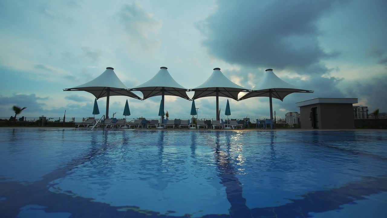 Shooting of the pool with pool umbrella and shades in the background. blue sky.