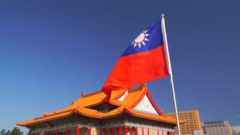 taiwanese flag in slow motion in wind with typical chinese shrine hall in distance