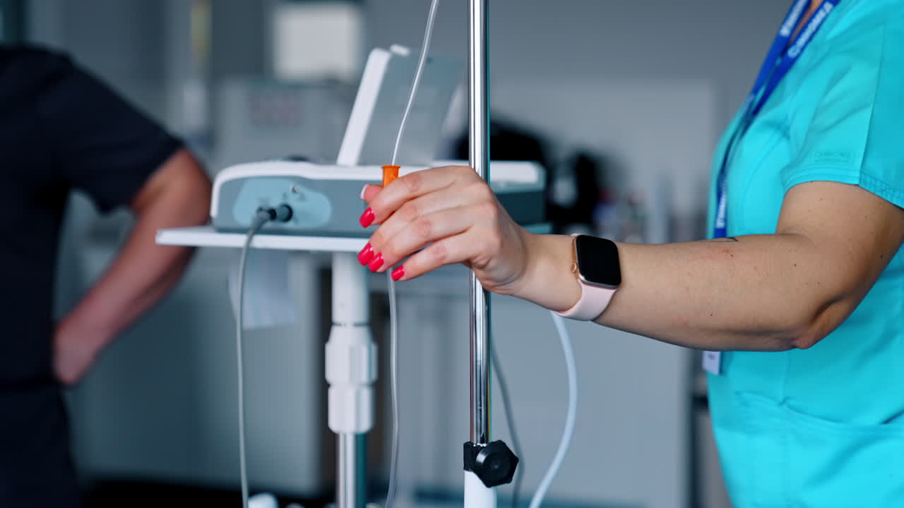 Caucasian nurse's hand sets the drop counter. Hospital equipment arranged for work. Blurred backdrop.