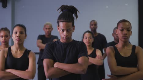 bailarín masculino moderno de raza mixta de pie frente a un grupo de bailarines masculinos y femeninos
