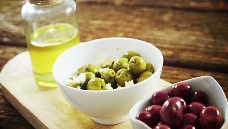 red and green olives and olive oil on wooden board