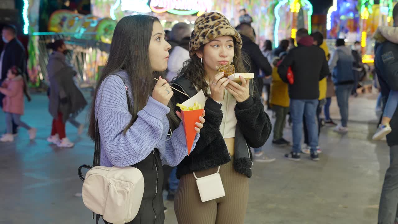 Two girls enjoying fries and a dessert at a fair