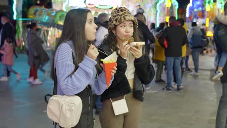 two girls enjoying fries and a dessert at a fair