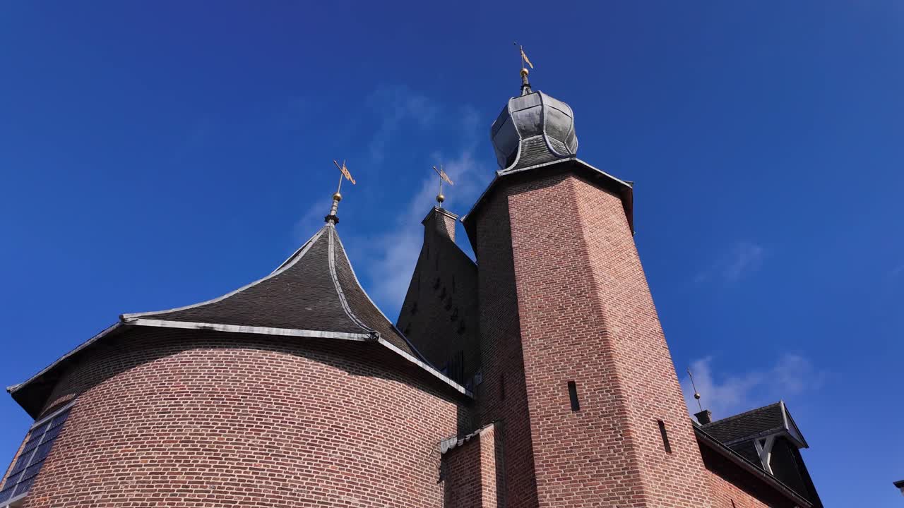 Low angle view of medieval castle towers with brick walls, pointed roofs and golden weather vanes against clear sky in Coevorden, Drenthe, Netherlands (Coevorden, Drenthe, Nederland)