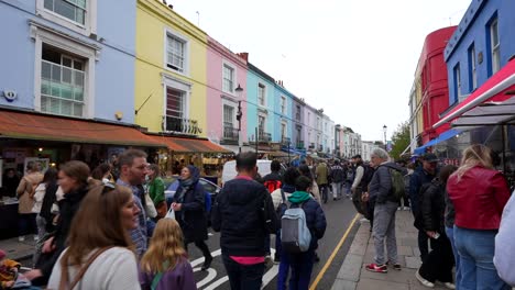 crowded portobello road market on cloudy day, notting hill, london. handheld
