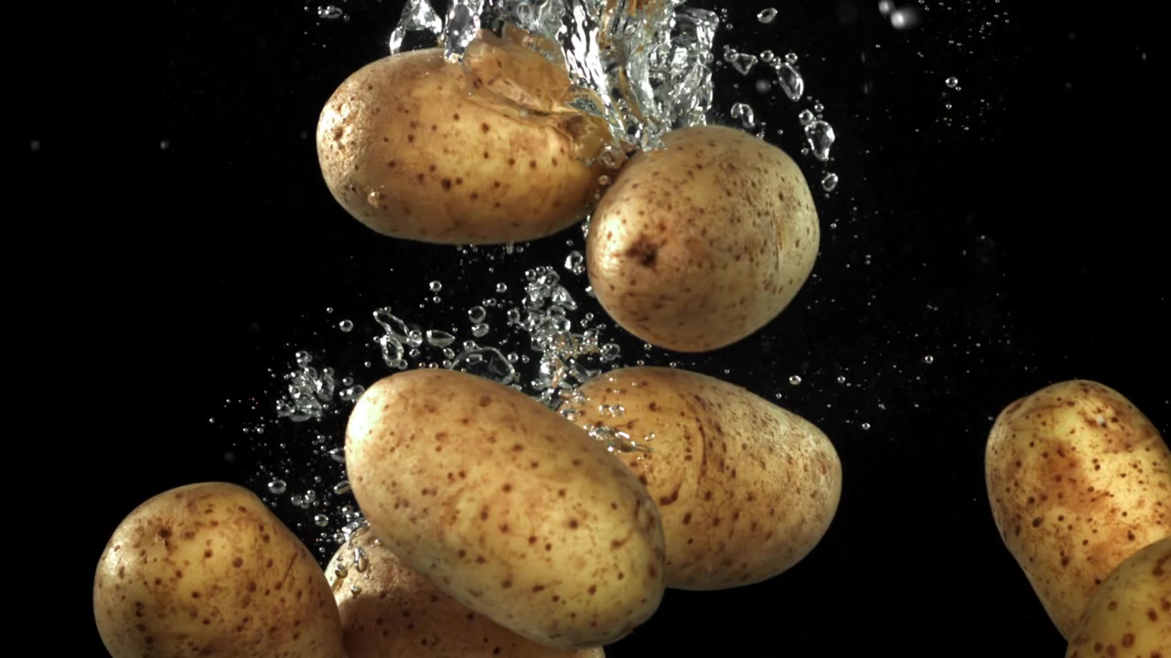 Patate fresche che cadono nell'acqua al rallentatore