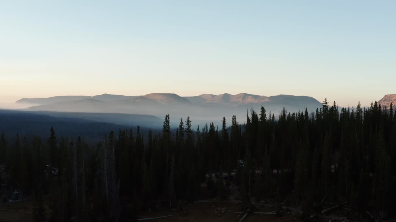 hermosa foto de un dron aéreo de camiones del impresionante bosque nacional salvaje uinta wasatch cache en utah con grandes pinos debajo e impresionantes montañas cubiertas de niebla en una mañana de verano
