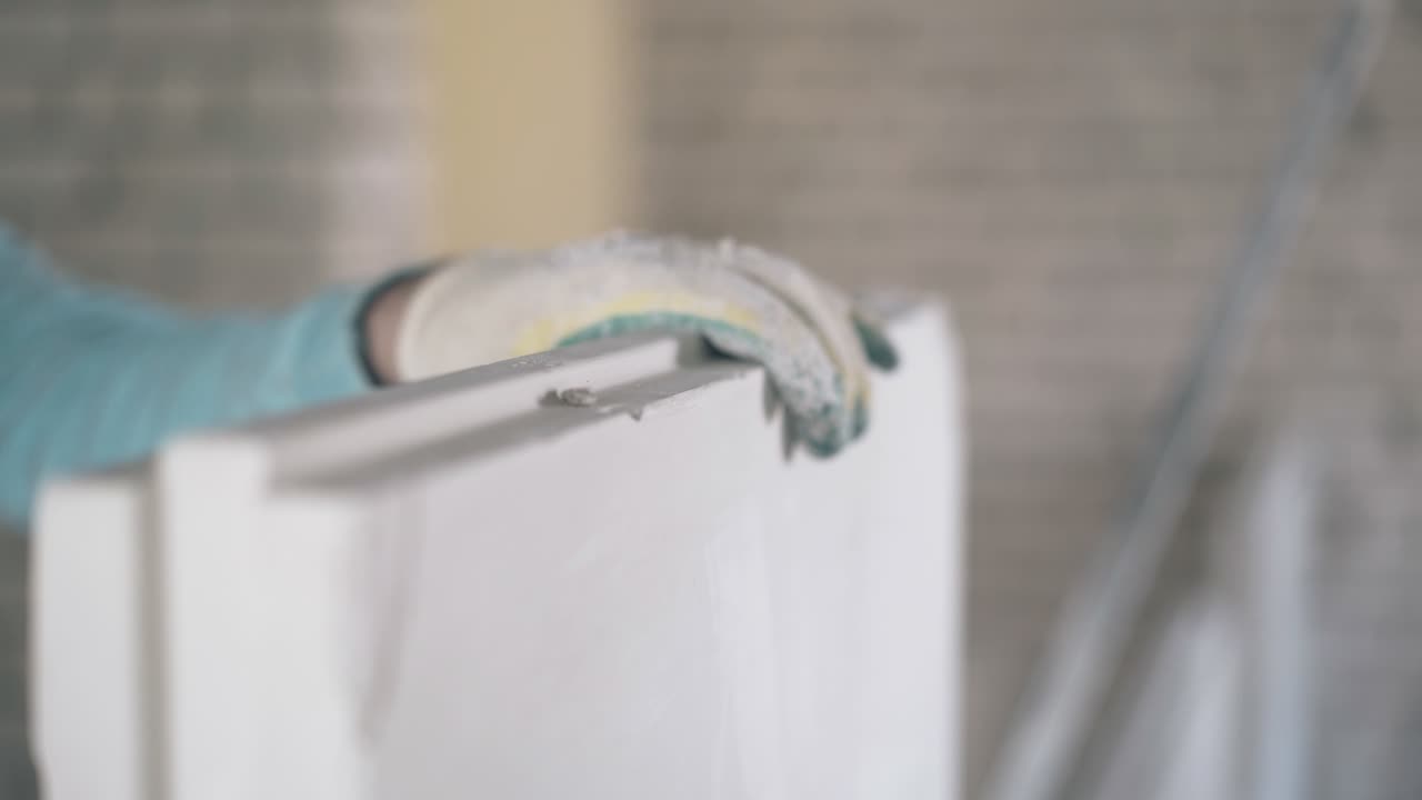 werknemer in handschoenen houdt gipsplatenconstructie vast