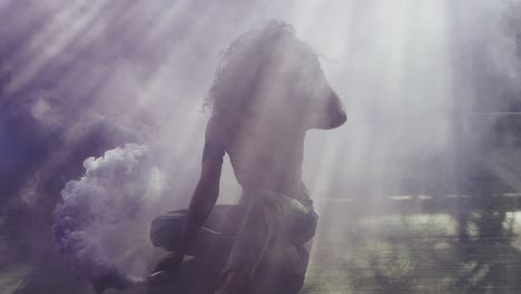 beautiful young woman modeling with purple smoke grenade in dramatic moody lighting