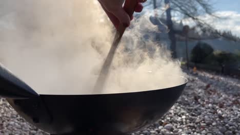 cooking in a wok over an open fire