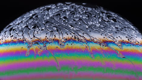 Close-up-footage-of-the-colourful-surface-of-a-soap-bubble-as-it-begins-to-break-down