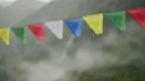 raining on buddhist prayer flags in rain in nepal in the himalyas mountains, close up in rainy season of heavy rain and tibetan prayer flags in the annapurna region trekking in nepal