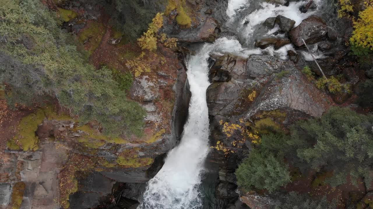 pintoresca cascada de agua se estrella a través de la montaña rocosa rodeada de pinos en alaska